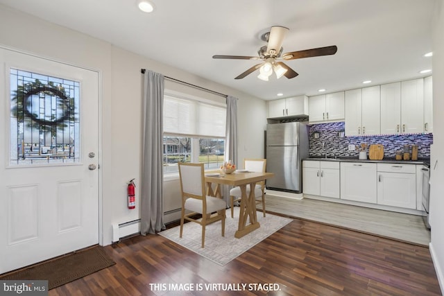 kitchen featuring wood finished floors, freestanding refrigerator, dark countertops, tasteful backsplash, and baseboard heating