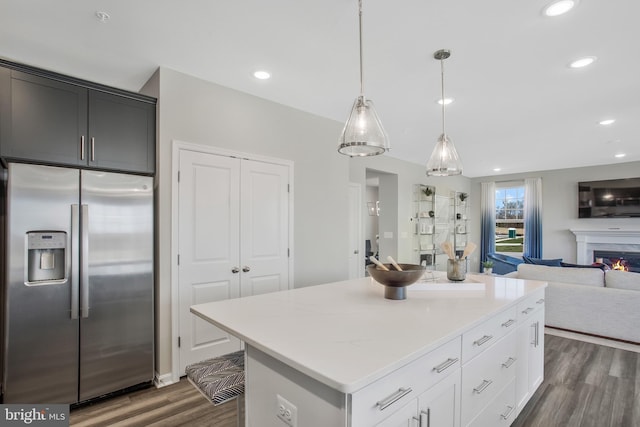 kitchen featuring stainless steel fridge, hanging light fixtures, white cabinets, a kitchen island, and dark hardwood / wood-style flooring