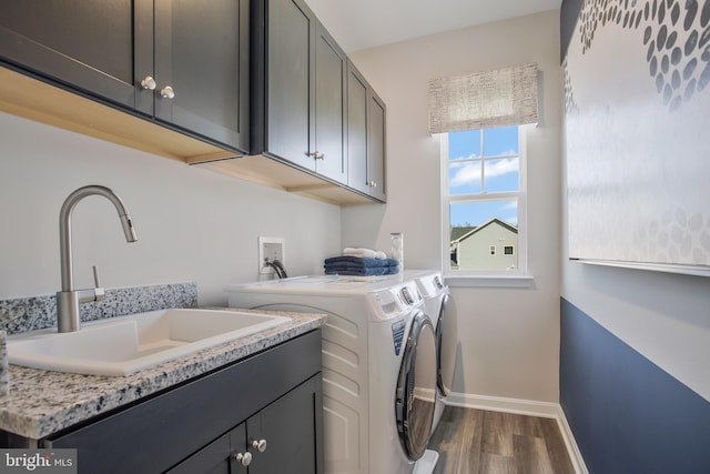 clothes washing area featuring cabinets, wood-type flooring, sink, and washer and dryer