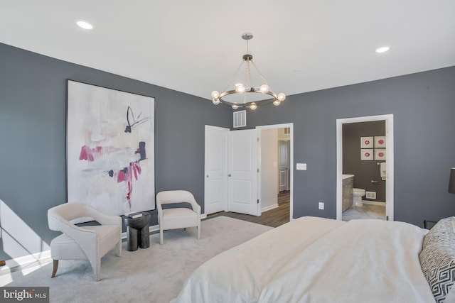 bedroom with an inviting chandelier, connected bathroom, and light hardwood / wood-style flooring