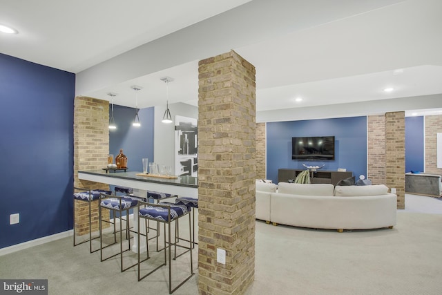 carpeted living room with bar area and decorative columns