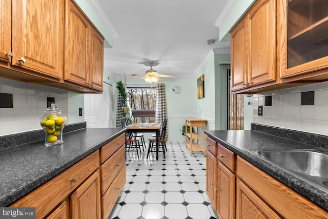 kitchen with sink, decorative backsplash, ornamental molding, and ceiling fan