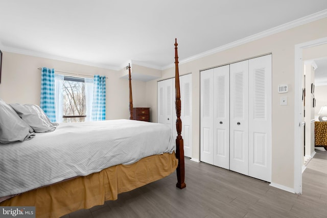 bedroom featuring multiple closets, crown molding, and light hardwood / wood-style floors