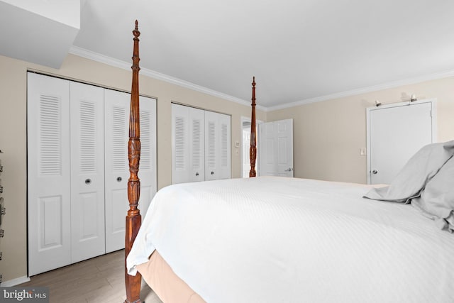 bedroom featuring two closets, ornamental molding, and light hardwood / wood-style floors