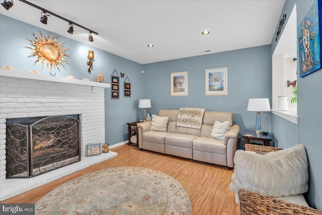 living room featuring hardwood / wood-style flooring, track lighting, and a fireplace