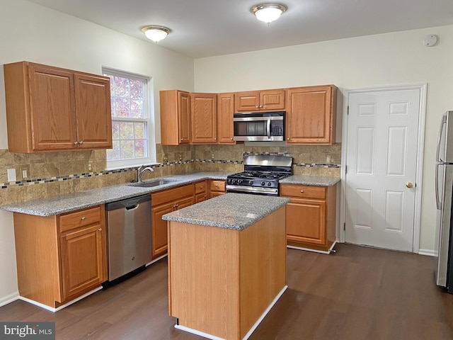 kitchen featuring sink, dark hardwood / wood-style flooring, a center island, stainless steel appliances, and light stone countertops