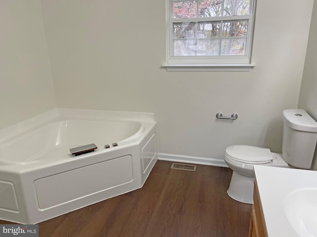 bathroom featuring vanity, hardwood / wood-style floors, toilet, and a bathing tub