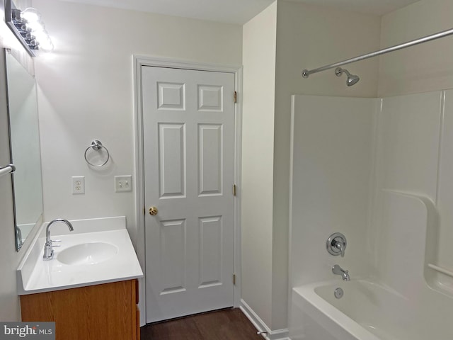 bathroom featuring hardwood / wood-style flooring, washtub / shower combination, and vanity