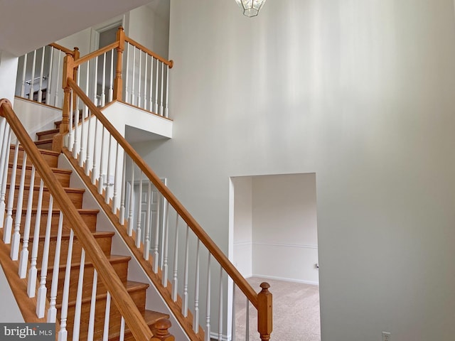 staircase featuring carpet flooring and a high ceiling