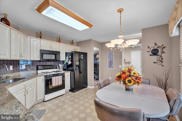 kitchen with decorative light fixtures, light stone countertops, sink, and black appliances