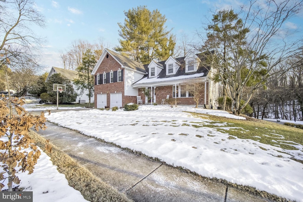 cape cod-style house featuring a garage and covered porch