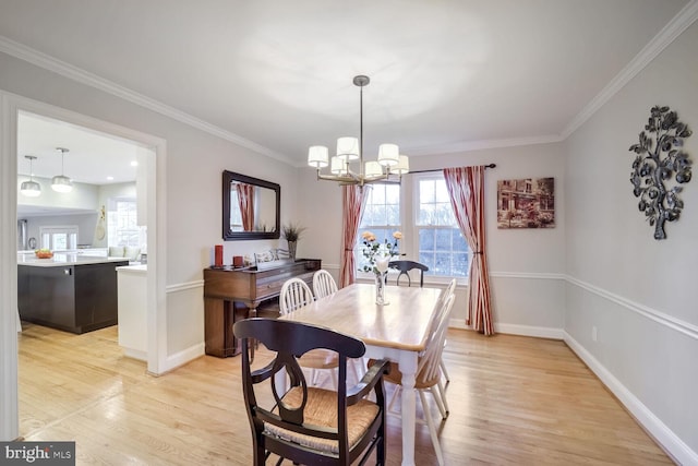 dining area featuring an inviting chandelier, ornamental molding, and light hardwood / wood-style flooring