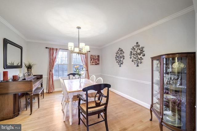 dining area with ornamental molding, light hardwood / wood-style floors, and a chandelier