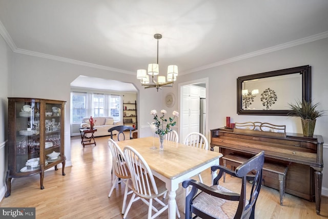 dining space featuring ornamental molding, a chandelier, and light hardwood / wood-style flooring