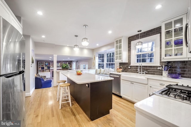 kitchen featuring hanging light fixtures, white cabinetry, appliances with stainless steel finishes, and a center island