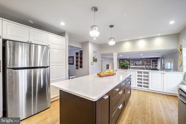 kitchen with white cabinetry, decorative light fixtures, light hardwood / wood-style floors, and appliances with stainless steel finishes