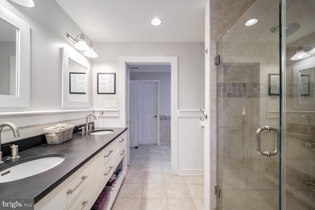 bathroom with a shower with door, vanity, and tile patterned flooring