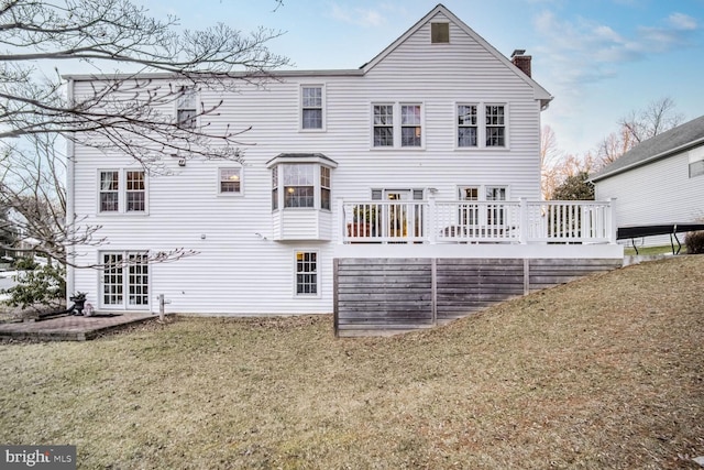 rear view of property featuring a yard, a deck, and french doors