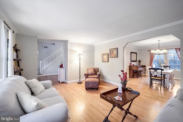 living room featuring ornamental molding, a chandelier, and light wood-type flooring