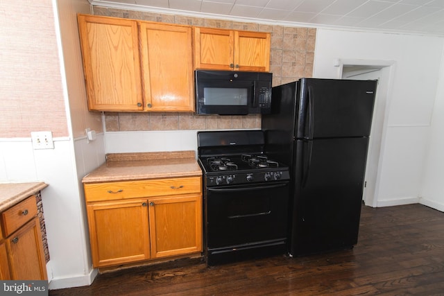 kitchen featuring black appliances, ornamental molding, light countertops, and dark wood-style flooring