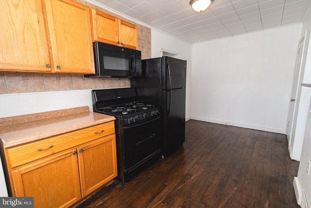 kitchen featuring black appliances, dark wood-style flooring, and light countertops