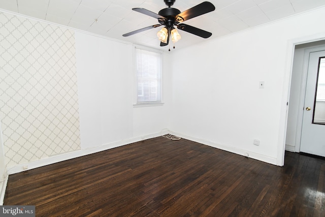 spare room with baseboards, ceiling fan, dark wood-style flooring, and crown molding