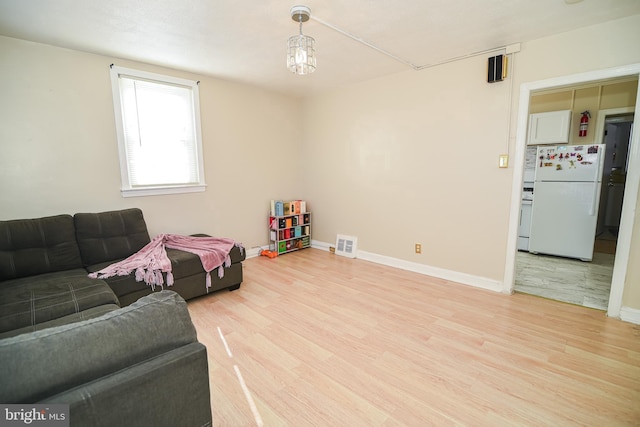 living area with light wood-style floors, visible vents, and baseboards