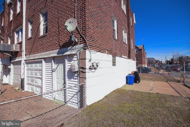 view of property exterior with a garage, fence, and brick siding