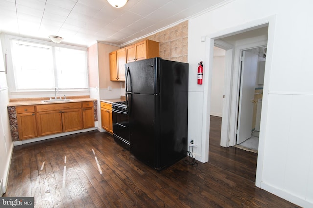 kitchen featuring a sink, light countertops, dark wood-style floors, black appliances, and crown molding