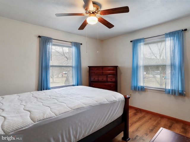 bedroom featuring multiple windows, wood-type flooring, and ceiling fan