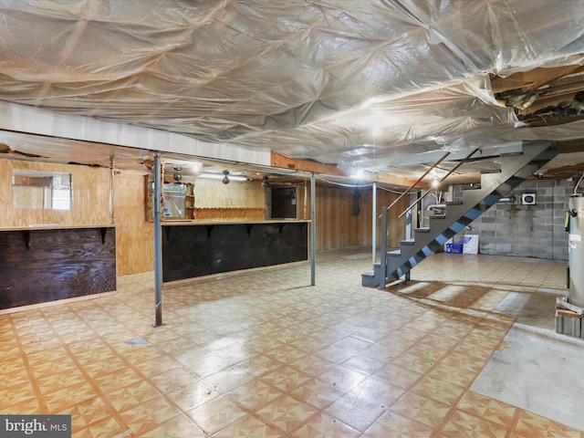 basement featuring wooden walls and water heater