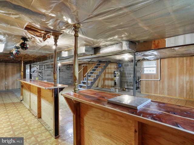 basement featuring wooden walls, bar area, and water heater