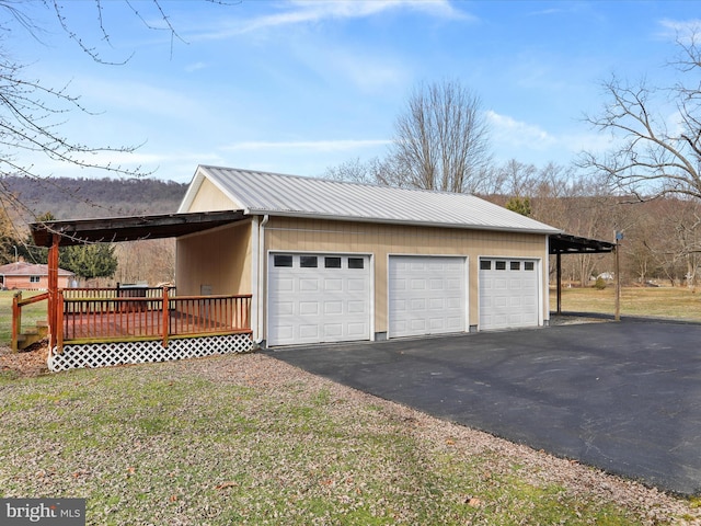 view of side of property with a garage, a carport, an outbuilding, and a deck