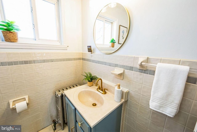 bathroom with vanity, radiator, and tile walls