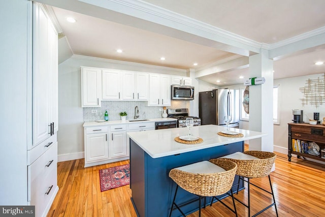 kitchen featuring white cabinetry, a kitchen bar, a center island, and appliances with stainless steel finishes