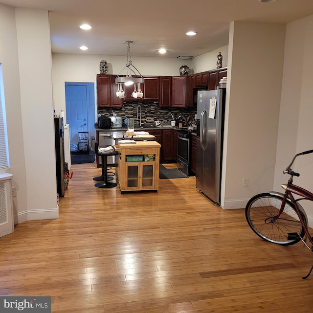 kitchen with a kitchen island, decorative light fixtures, tasteful backsplash, sink, and stainless steel appliances