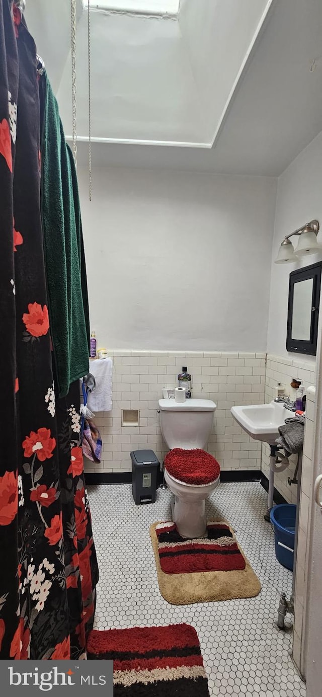 bathroom with sink, tile walls, tile patterned floors, and toilet