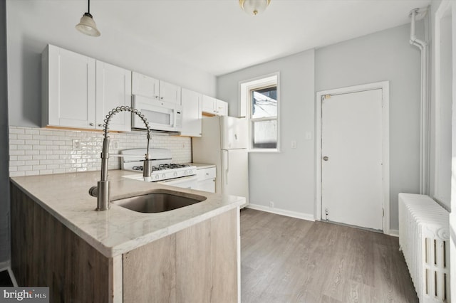 kitchen featuring pendant lighting, radiator heating unit, white cabinets, and white appliances