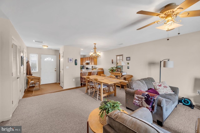 carpeted living room featuring ceiling fan with notable chandelier