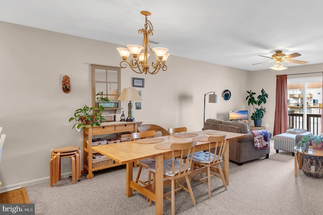 dining area featuring ceiling fan with notable chandelier and carpet flooring