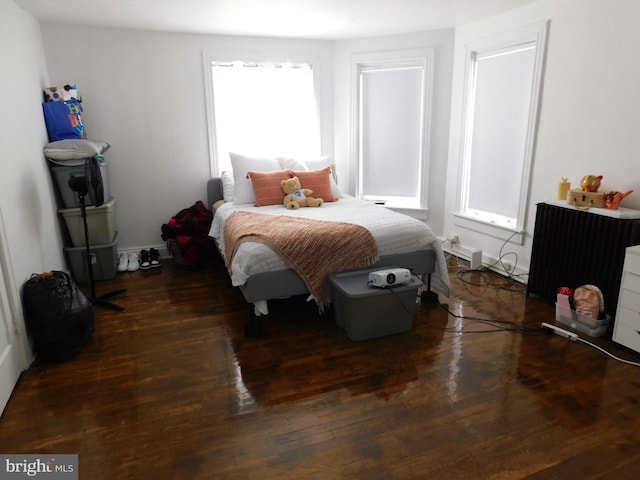 bedroom with radiator heating unit and dark hardwood / wood-style floors