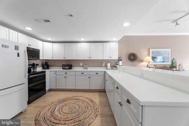 kitchen with white cabinetry, white appliances, kitchen peninsula, and light hardwood / wood-style floors