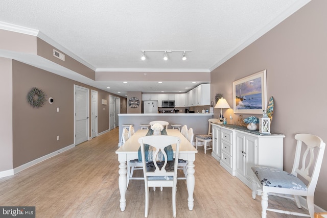 dining room with crown molding, a textured ceiling, and light wood-type flooring