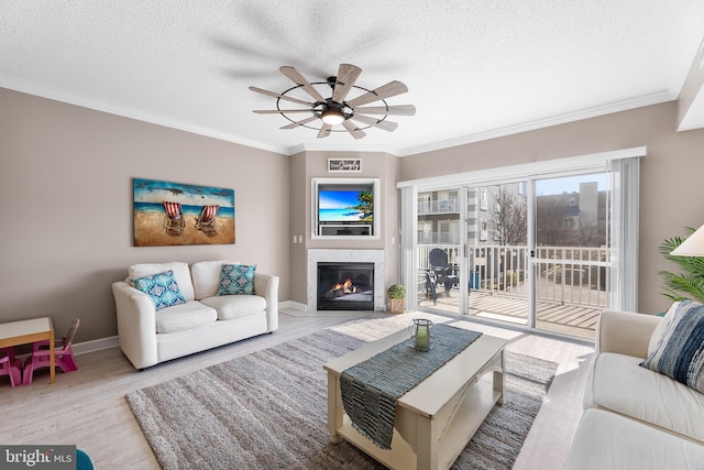 living room featuring ornamental molding, a textured ceiling, and light hardwood / wood-style floors