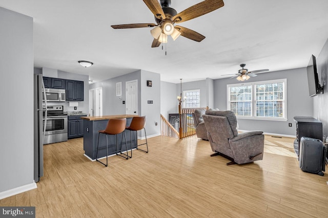 living room with ceiling fan with notable chandelier and light hardwood / wood-style floors