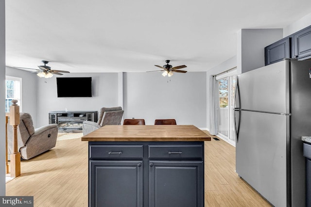 kitchen with ceiling fan, stainless steel fridge, butcher block countertops, and light hardwood / wood-style flooring