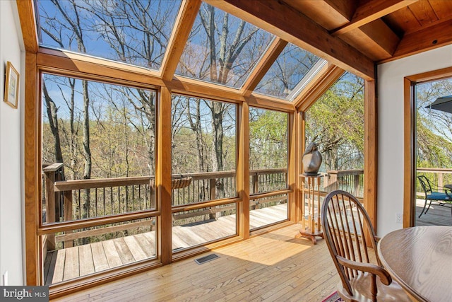 sunroom featuring visible vents, beam ceiling, a deck, and hardwood / wood-style floors