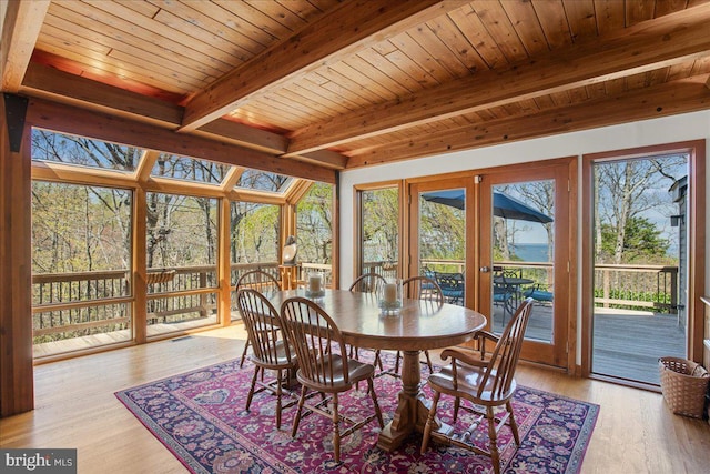 dining room with plenty of natural light, light wood-style floors, wood ceiling, and beamed ceiling