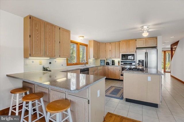 kitchen with a healthy amount of sunlight, light brown cabinetry, backsplash, and stainless steel appliances