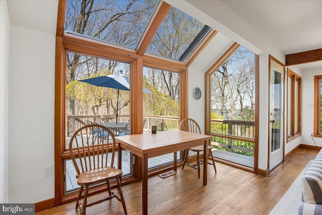 sunroom with baseboards, visible vents, plenty of natural light, and wood finished floors